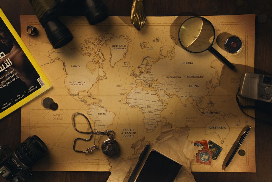 A still life composition of vintage travel items including a world map, camera, and magnifying glass.